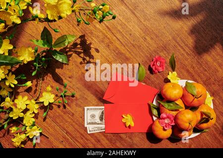 Branches de l'abricotier en fleurs, fruits et des enveloppes rouges avec de l'argent réparé pour le Nouvel An lunaire Banque D'Images