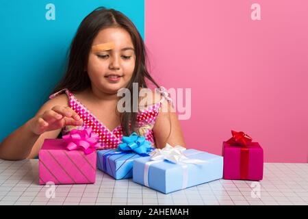 Jeune fille asiatique assis à une table avec des présents, des cadeaux à choqué et heureux - l'enfance célébrations et événements concept Banque D'Images