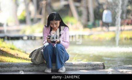 Style de sourire jolie jeune femme s'amuser dans le jardin, avec un appareil photo de voyage du photographe. Banque D'Images