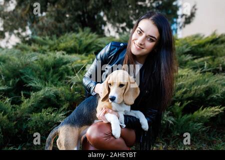 Jolie fille brune prend dans les bras de son bien-aimé chien mignon. Banque D'Images