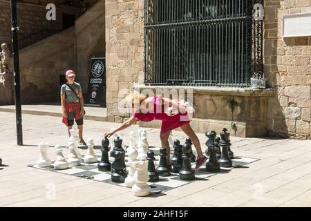 Barcelone, Espagne - 28 juin 2019 : Une mère et son fils jouer avec un échiquier géant sur la place de l'ancien hôpital médiéval, dans le quartier du Raval, Banque D'Images