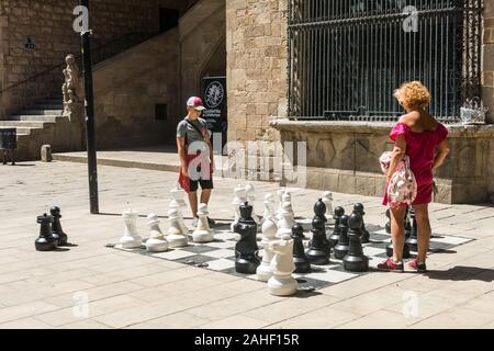 Barcelone, Espagne - 28 juin 2019 : Une mère et son fils jouer avec un échiquier géant sur la place de l'ancien hôpital médiéval, dans le quartier du Raval, Banque D'Images