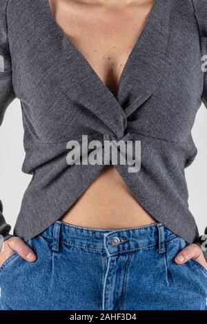 Cute young woman in sweater et jeans à marcher en direction de caméra avec les mains dans les poches. Corps plein isolé sur fond blanc. Banque D'Images