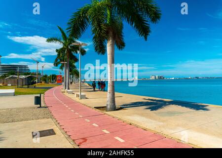 Luanda, Angola - 15 décembre 2019: Les gens marchant une journée ensoleillée à la baie de Luanda. Illustration éditoriale. Banque D'Images