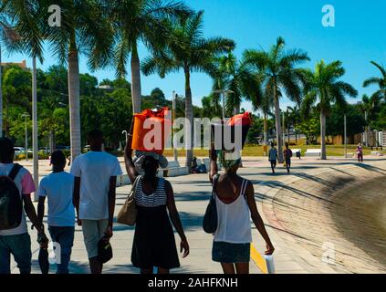 Luanda, Angola - 15 décembre 2019: Les gens marchant une journée ensoleillée à la baie de Luanda. Illustration éditoriale. Banque D'Images