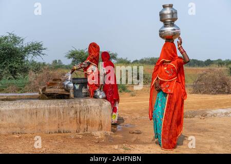 Kalbeliya femmes gitanes dans des vêtements colorés collecter et transporter sur leur tête l'eau potable au robinet public dans désert du Thar. Pushkar, Rajasthan, Inde. Banque D'Images