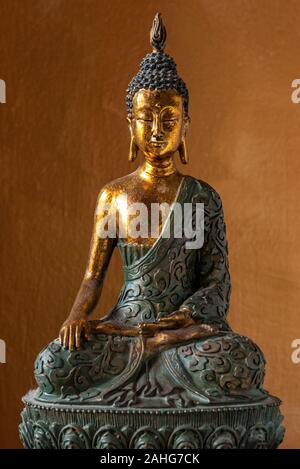 Statue de Bouddha en bois assis en méditation sur fond orange Banque D'Images