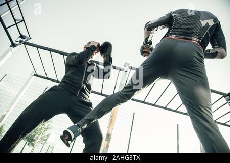 Boxeur MMA cachant sa tête tout en ayant l'entraînement avec partenaire de sport Banque D'Images