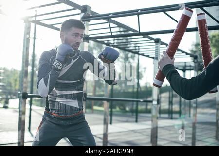 Confiant la maîtrise de son boxer poinçons et regardant les bâtons de boxe Banque D'Images