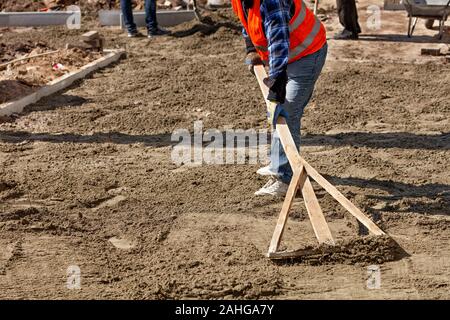 Les niveaux d'un travailleur le sable avec un niveau de base en bois pour commencer à jeter des dalles dans la zone piétonne de la ville, image avec copie espace. Banque D'Images