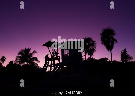 Silhouette de baywatch tower et de palmiers au coucher du soleil à Playa del Carmen, Mexique. Lifeguard structure en bois au crépuscule par mer des Caraïbes Banque D'Images