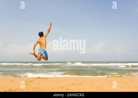 Jeune homme faisant un saut acrobatique sur la plage vide à Bentota, au Sri Lanka. Bliss, sentiment de plaisir, concept d'émotion de bonheur Banque D'Images