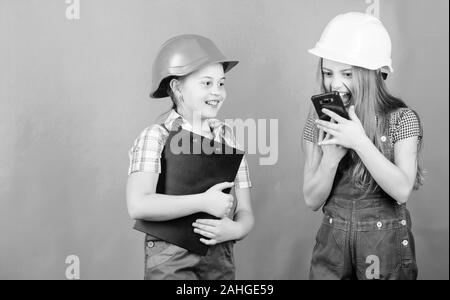 La fête du travail. 1 mai. Projet d'école. Inspecteur de contremaître. La réparation. Les petits enfants en casque avec tablette. petites filles réparer ensemble en atelier. crier sur travailleur dans l'appel téléphonique. discuter de problèmes. Banque D'Images