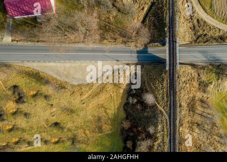 Pont de chemin de fer entre les prairies vertes sur la route à la campagne, vue aérienne Banque D'Images