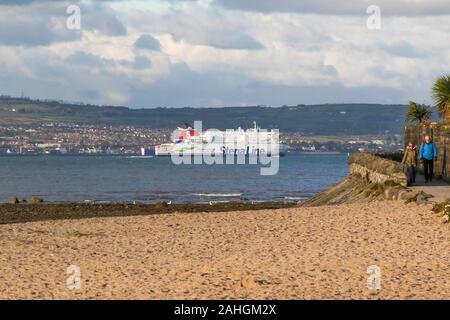 Un homme et une femme marchant sur le sentier du littoral sur Belfast Lough, le Stena Line ferry navigue vers le bas sur le lac de Belfast une après-midi ensoleillée d'automne. Banque D'Images