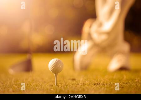 Close up sur balle de golf sur tee, chaussures de golf et d'un angle faible bois fond sun flare Banque D'Images