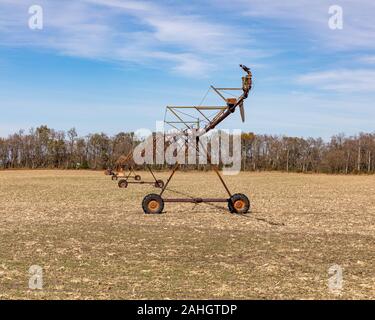 Rusty, ancien système d'irrigation à pivot central dans un champ avec des arbres récoltés, ciel bleu, et les nuages blancs en arrière-plan Banque D'Images