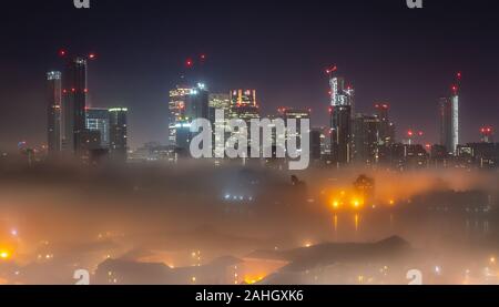 Londres, Royaume-Uni. 30 Décembre, 2019. Météo France : une couche de brouillard mystique couverture plane sur l'Est de Londres à minuit avec Canary Wharf se lever au-dessus des bâtiments. Crédit : Guy Josse/Alamy Live News Banque D'Images