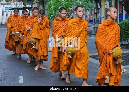 Jeune novice moines bouddhistes résident à Wat Mahathat à Bangkok, Thaïlande, avec leurs aumônes bols sur leur droit coutumier matin alms à pied Banque D'Images