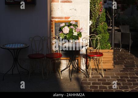 Chaises et table dans l'ombre le long du mur. Un café en plein air l'Europe. Banque D'Images