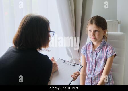 Femme travailleur social psychologue parler aux petites filles dans office, conseillère en prenant des notes dans le presse-papiers. La santé mentale des enfants Banque D'Images