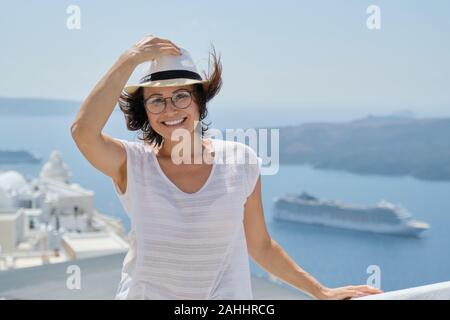 Portrait de femme d'âge moyen voyageant sur croisière de luxe en Méditerranée. Female looking at camera sur l'île de Santorin, copy space Banque D'Images