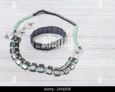 Needlecraft Contexte - collier artisanal du vert jade, hématite noir et argent et hématite bracelet sur planche en bois gris avec copyspa Banque D'Images