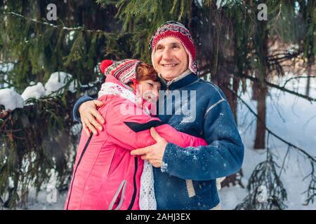 Le jour de la Saint-Valentin. Famille Senior couple hugging in winter forest. Heureux l'homme et de la femme la marche à l'extérieur. Banque D'Images