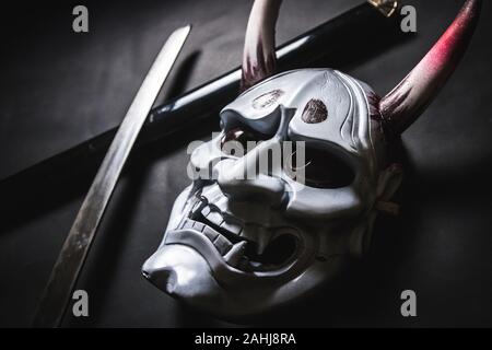 Oni japonais ou masque masque géant, utilisé pour décorer la main à partir de l'original pour lui donner l'air et de l'art sombre, avec katana sword Banque D'Images