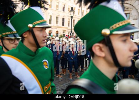 Les membres de la Glenbrook North High School Spartan Marching Band, de l'Illinois, USA, (premier plan) et les interprètes de la carnaval del Pueblo pendant un essai de Londres le défilé du Nouvel An à la Piazza de Covent Garden à Londres. Banque D'Images