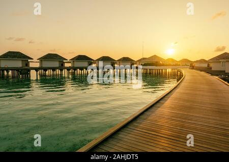 Jetée en bois et la ligne de temps au lever du soleil villas tropicales, Maldives Banque D'Images