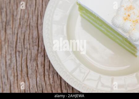 Libre vert doux la crème de coco gâteau dans un article sur l'assiette propre au bord de l'espace, mettre sur la table en bois écorce texture Banque D'Images