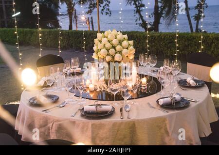 Configuration de table de dîner pour cérémonie de mariage à l'extérieur dans la nuit avec vue sur la plage, décorer avec des fleurs de lotus dans le style indien Banque D'Images