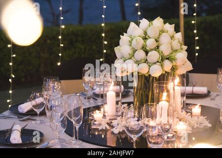 Configuration de table de dîner pour cérémonie de mariage à l'extérieur dans la nuit avec vue sur la plage, décorer avec des fleurs de lotus dans le style indien Banque D'Images