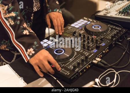 DJ dans tiger pattern shirt est de mélanger un peu de musique avec le contrôleur dans la chambre en déplaçant les mains pour régler le bouton Banque D'Images