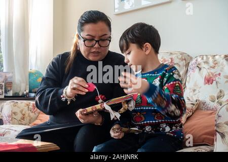 Une mère et son jeune fils avec excitation ouvrir un cadeau de Noël ensemble Banque D'Images
