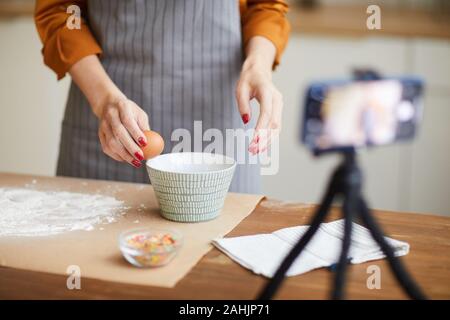 Portrait Portrait de jeune femme méconnaissable casser des œufs lors d'un tournage vidéo tutoriel pour cuisson channel, copy space Banque D'Images