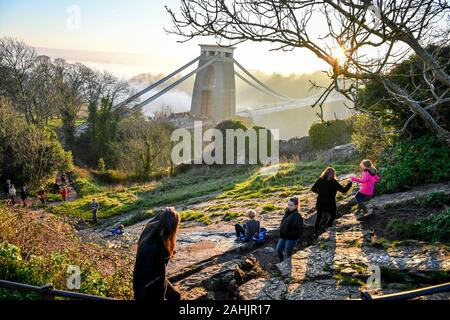 Les gens jouent sur une diapositive naturel formé dans la roche à côté du pont suspendu de Clifton à Bristol, où le faible brouillard recouvre la ville. Banque D'Images