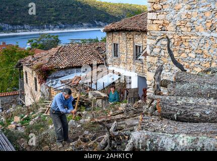 Couper le bois pour l'hiver dans le petit village de pêcheurs sur le lac Prespa Psarades étonnant avec de la Macédoine, la Grèce du Nord. Banque D'Images