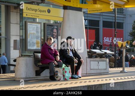 Couple en attente à l'arrêt de tramway Exchange Square, Manchester City Centre Banque D'Images