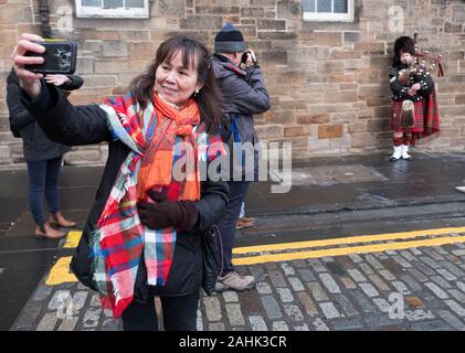 Photographier un piper de la rue touristique sur le Royal Mile, Édimbourg, Écosse. Banque D'Images