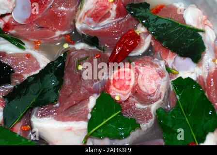 Cuisine calabraise. Mariner l'agneau pickled avec du vin blanc, des feuilles de laurier, du romarin et du piment rouge chaud. Banque D'Images