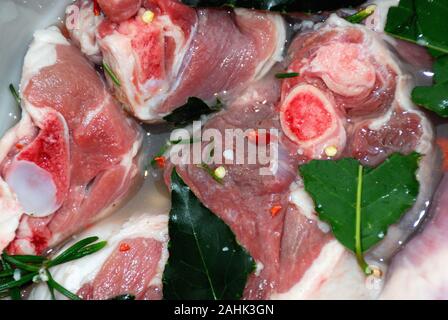 Cuisine calabraise. Mariner l'agneau pickled avec du vin blanc, des feuilles de laurier, du romarin et du piment rouge chaud. Banque D'Images