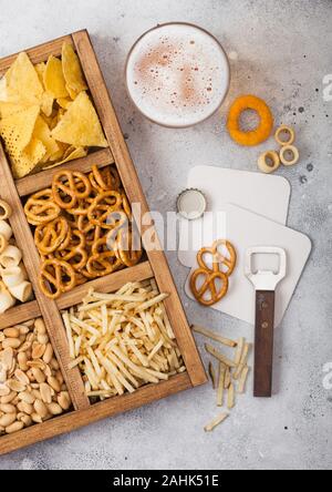 Verre de bière blonde artisanale et l'ouvreur avec fort d'en-cas sur la lumière d'arrière-plan de cuisine. Bretzel,salé aux noix, arachides, oignons avec nachos dans Banque D'Images