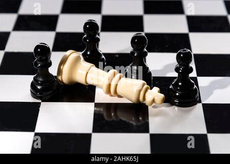 Chess est photographié sur un échiquier. Pions blancs entouré le défait queen noir sur la table d'échecs Banque D'Images