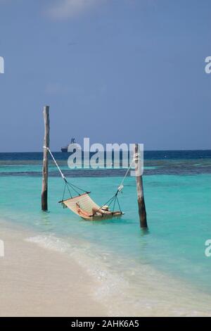 Femme portant un bikini et un chapeau, de détente dans un hamac dans la mer à Bandos Island, Maldives, océan Indien Banque D'Images