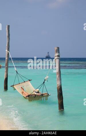 Femme portant un bikini et un chapeau, de détente dans un hamac dans la mer à Bandos Island, Maldives, océan Indien Banque D'Images