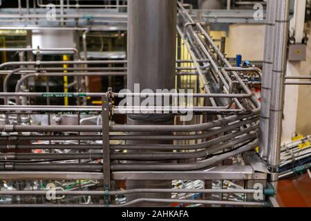 Un complexe système de tuyauterie, de l'eau chaude canalisations métalliques avec des fils, zone de conditionnement, systèmes de convoyeur à courroie en arrière-plan, l'usine de bière brasserie Banque D'Images