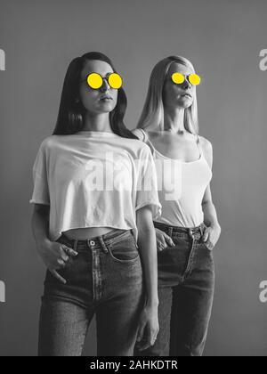 Technique mixte poster avec deux filles photo en noir et blanc avec deux jeunes filles en jaune lunettes peintes dans des vêtements décontractés Banque D'Images