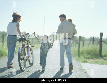 Une famille heureuse est de prendre une marche le long d'une route dans la campagne. Banque D'Images